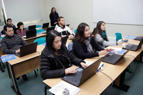 Un grupo de estudiantes se encuentra en un aula utilizando computadoras portátiles.