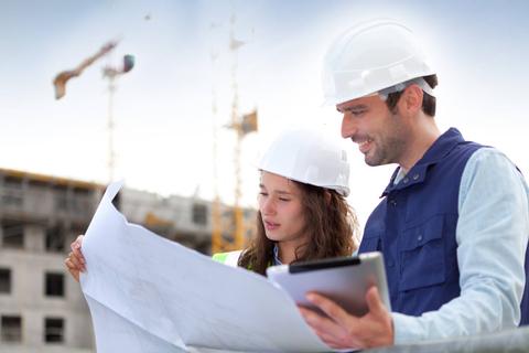 Dos trabajadores de la construcción revisan planos en un sitio de obra.