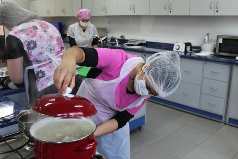 Varias personas están cocinando en una cocina equipada.