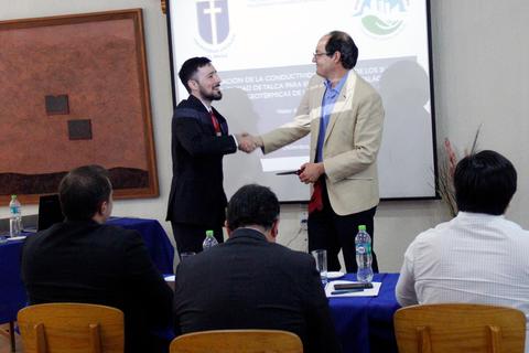 Dos hombres en un ambiente formal estrechan manos tras una presentación.