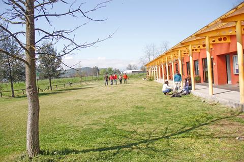 Una vista de un área al aire libre con un grupo de personas y un edificio colorido bajo un cielo despejado.