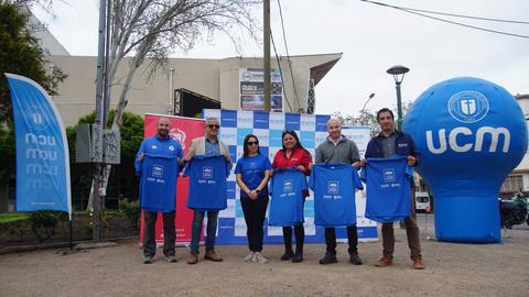 Un grupo de personas posando con camisetas azules en un evento al aire libre.