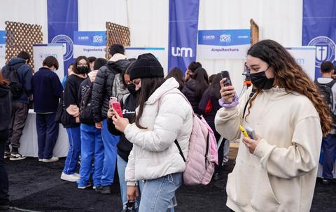 Grupo de estudiantes en un evento educativo interactuando con sus dispositivos móviles.