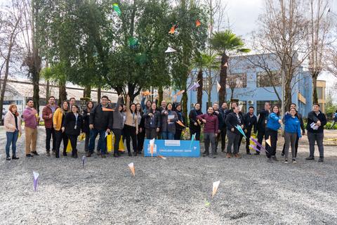 Un grupo de personas se reúne al aire libre frente a un edificio, celebrando con confeti de colores.