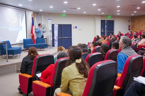 Una charla educativa se lleva a cabo en un auditorio con asistentes atentos.