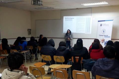 Una presentación en un aula con estudiantes sentados y una expositora de pie.