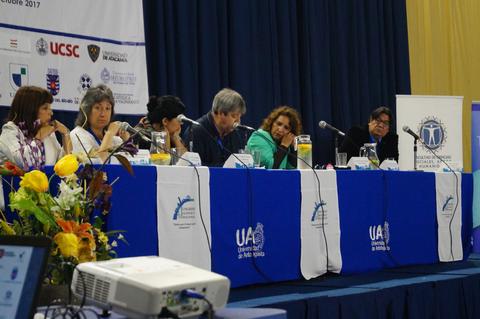 Una mesa redonda con varios panelistas discutiendo en un evento académico.