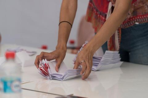 Una persona está organizando un montón de hojas sobre una mesa.