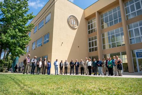 Un grupo de personas de pie frente a un edificio moderno con un logotipo en la fachada.
