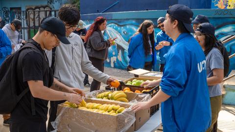 Un grupo de jóvenes distribuyendo frutas en una actividad comunitaria.