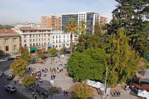 Una vista aérea de una plaza con árboles, edificios y personas reunidas.
