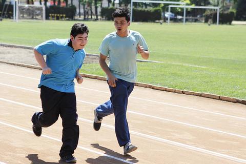 Dos jóvenes corren en una pista de atletismo durante una actividad al aire libre.