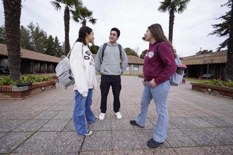 Tres jóvenes conversando en un ambiente al aire libre.