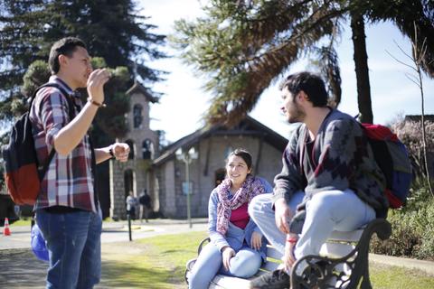 Tres jóvenes conversan y disfrutan al aire libre en un parque.