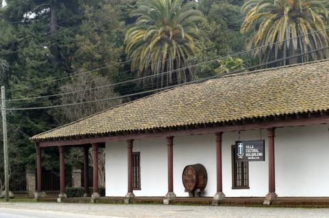 Una construcción de estilo colonial con palmeras al fondo y un letrero que indica 'Villa Cultural San Joaquín'.