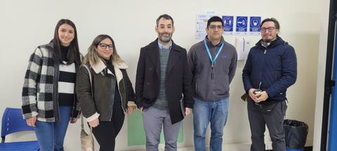 Un grupo de cinco personas posando en un lugar cerrado.