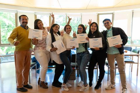 Un grupo de personas sonrientes sostiene certificados en un ambiente alegre.