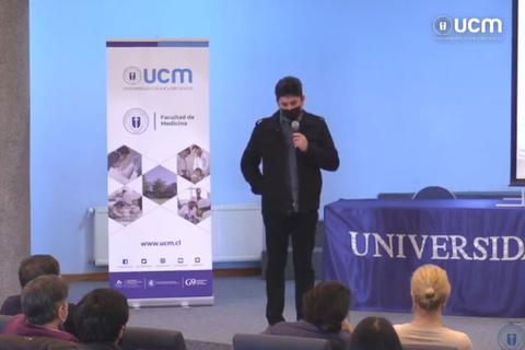 Un ponente se encuentra de pie frente a una audiencia en un evento académico en la Facultad de Medicina.