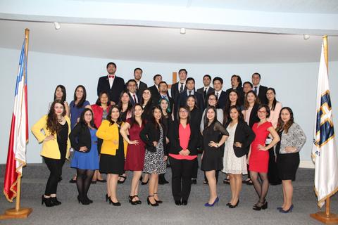 Grupo de personas posando en un evento formal con banderas en los laterales.