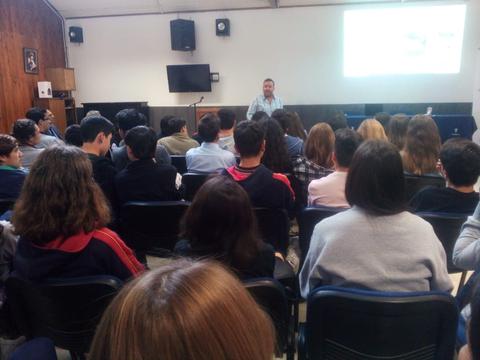 Un grupo de personas sentadas en un aula mientras un orador presenta frente a ellos.