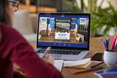 Una persona trabaja en un ordenador portátil con una presentación virtual de Expo UCM en la pantalla.