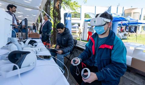 Una persona está usando un visor de realidad virtual en un evento al aire libre.