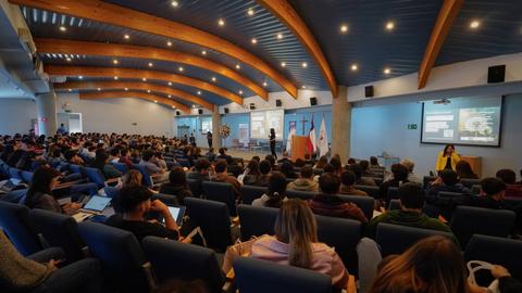 Una sala de conferencias con un gran número de asistentes prestando atención a una presentación.