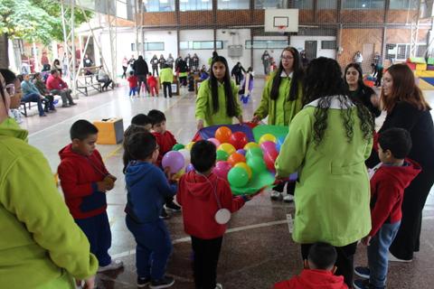 Niños y adultos juegan juntos con globos en una actividad recreativa en el gimnasio.