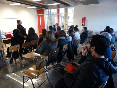 Una persona está dando una charla a un grupo de personas sentadas en un aula.
