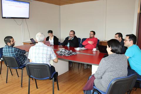 Un grupo de personas se encuentra discutiendo alrededor de una mesa en una sala de reuniones.