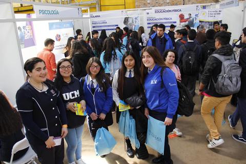 Un grupo de estudiantes sonríe frente a un stand en un evento educativo.