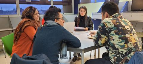 Un grupo de personas discutiendo en una mesa en un ambiente de trabajo.