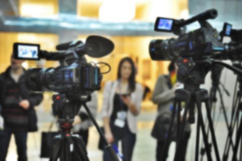 Un grupo de cámaras de video enfocando a una persona en un evento.