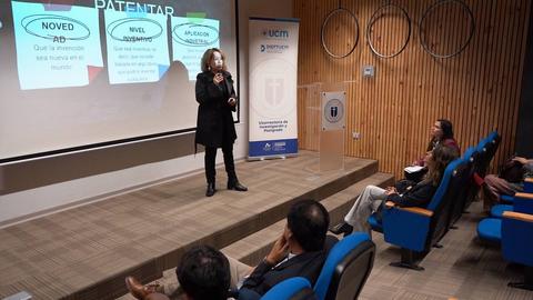 Una presentadora habla sobre patentes en un evento mientras el público escucha atentamente.