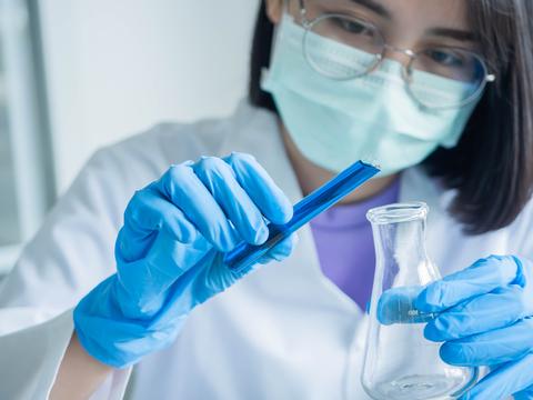 Una persona en un laboratorio lleva a cabo un experimento con un matraz.