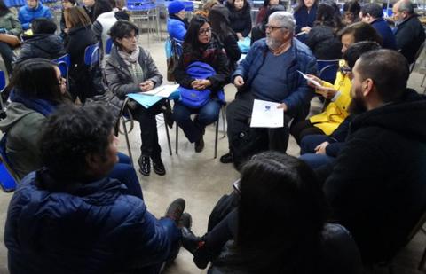 Un grupo de personas está sentando en círculo, participando en una conversación en un ambiente social.