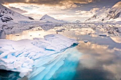 Una vista impresionante de un paisaje glacial con agua reflejando las montañas y un cielo nublado.
