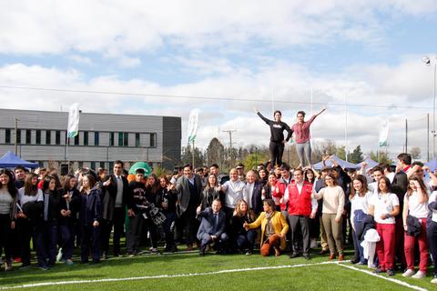 Un gran grupo de personas se reúne en un campo deportivo para una celebración.