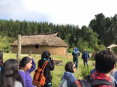 Una reunión de personas frente a una construcción tradicional rodeada de naturaleza.