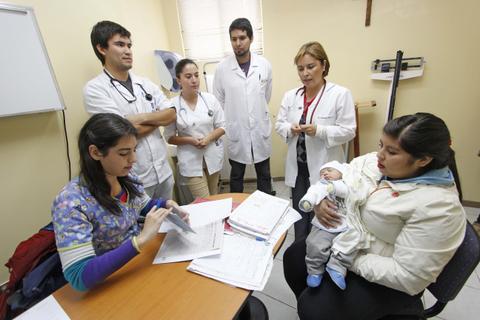 Un grupo de profesionales de la salud atiende a una madre con un bebé en una consulta médica.