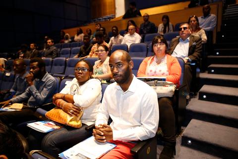 Una audiencia atenta en un evento, con diferentes personas sentadas y mirando hacia adelante.