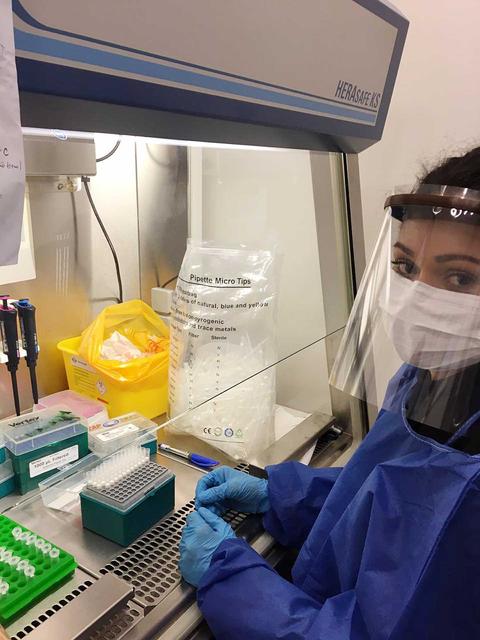 Una persona trabaja en un laboratorio utilizando equipo de protección y herramientas de pipeteo.