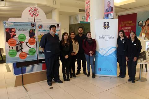 Un grupo de personas posando en un espacio institucional con paneles informativos sobre salud y educación.
