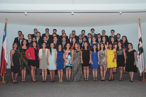 Un grupo grande de personas posando en un evento formal, con banderas de Chile en el fondo.