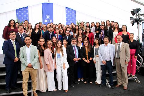 Grupo de personas posando en un evento formal bajo una carpa.