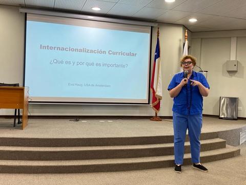Una persona presenta el tema de internacionalización curricular en un aula con una proyección detrás.