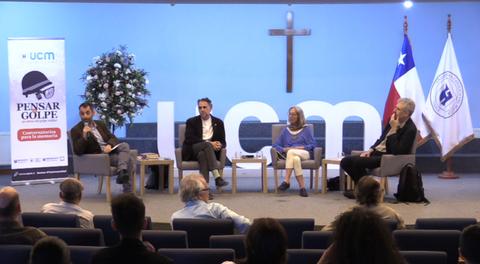 Una mesa de debate sobre el golpe de Estado en Chile en un auditorio con personas sentadas y panelistas discutiendo.