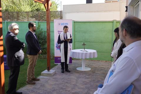Una ceremonia al aire libre con personas reunidas alrededor de una mesa cubierta en un jardín.