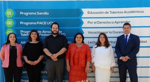 Un grupo de seis personas posando frente a un fondo con información sobre programas educativos.