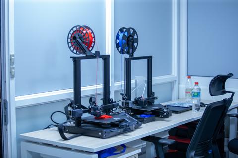 Dos impresoras 3D trabajando en un ambiente de oficina.